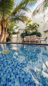 延布ريفان لبيوت الضيافة خاصة的一个带蓝色瓷砖地板和棕榈树的游泳池