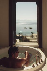 莫拉蒂卡Domes Miramare, a Luxury Collection Resort, Corfu - Adults Only的浴缸里的人,享有海景