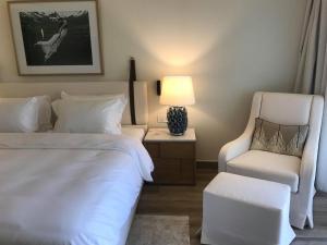 莫拉蒂卡Domes Miramare, a Luxury Collection Resort, Corfu - Adults Only的一间卧室配有一张床、一把椅子和一盏灯