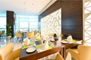 多哈Ramada Encore Doha by Wyndham的一间带桌子和黄色椅子的用餐室