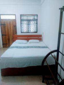 锡吉里亚Sigiriya Guest House Inamaluwa的一间卧室配有一张大床和木制床头板