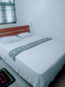 锡吉里亚Sigiriya Guest House Inamaluwa的一张白色大床,带有木制床头板