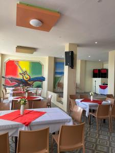 波尔多·格尼拉Hotel Dorotea的餐厅设有桌椅,墙上挂有绘画作品