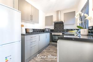 利Severn Street House Serviced Accommodation的厨房配有白色橱柜和黑色台面