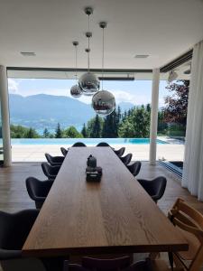 阿特湖畔努斯多夫Attersee Luxury Design Villa with dream views, large Pool and Sauna的一张长木桌子和椅子,位于一个设有大窗户的房间