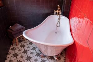 托莱多RIAD MEDINA MUDEJAR BAÑOS ARABES的带浴缸的浴室和红色的墙壁