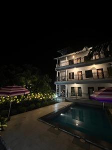 阿利鲍格iIRA Stays-Awas Beach Resort - Pet Friendly的夜间的酒店,前面有一个游泳池