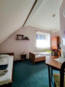 格涅夫Hotel Na Wzgórzu的客房设有两张床、一张桌子和一扇窗户。