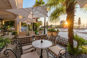 奥帕提亚Hotel Palace Bellevue - Liburnia的一个带桌椅和棕榈树的庭院