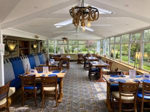 克利夫罗Calf's Head Hotel的餐厅设有木桌、椅子和窗户。
