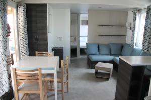 拉特斯mobil home au lac des rêves的客厅配有桌子和蓝色沙发