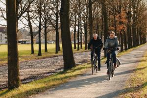WestmalleDe Kasteelhoeve的两个人骑着自行车沿着公园的小径骑着