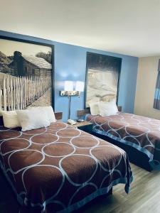 科尔宾Super 8 by Wyndham Corbin KY的酒店客房设有两张床,墙上挂有绘画作品