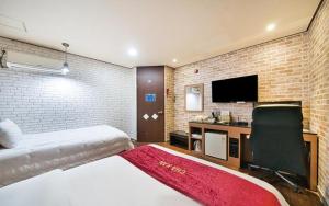 群山市Chakan Hotel的一间卧室配有一张床和一张书桌及电视