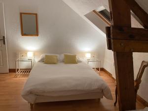 Gîte Utah du DOMAINE DE SAINT-VIGOR的一间卧室配有一张带两张桌子和两盏灯的床。