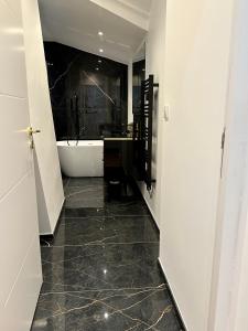 兰斯Bel Appartement avec parking au coeur de Reims的带浴缸的浴室和黑色瓷砖地板。