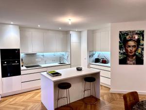 兰斯Bel Appartement avec parking au coeur de Reims的厨房配有白色橱柜和带凳子的台面