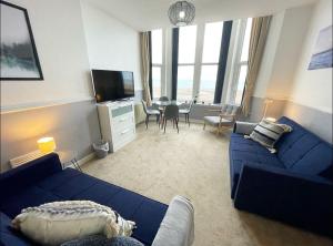 锡斯凯尔6 Burnett by Prestige Properties SA的客厅配有蓝色的沙发和电视