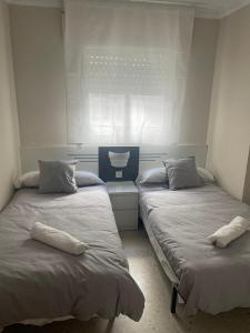 桑卢卡尔-德巴拉梅达Apartamento Acogedor的客房设有两张带枕头的床和窗户。