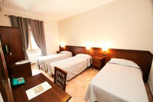 蒙塔尔托迪卡斯特罗HOTEL VULCI的酒店客房设有三张床和一张桌子