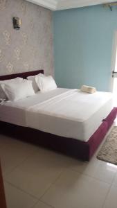 科托努HÔTEL NOAHGARDEN 2的卧室配有一张带白色床单和枕头的大床。