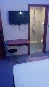 科托努HÔTEL NOAHGARDEN 2的一间卧室设有淋浴和一张带电视的长凳。