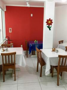 马卡埃Pousada Bem Brasil的一间设有两张桌子和红色墙壁的餐厅