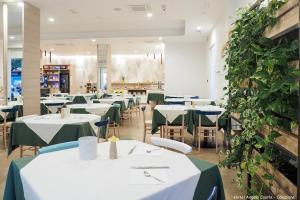 卡奥莱安杰洛酒店的用餐室配有白色桌子和绿色植物