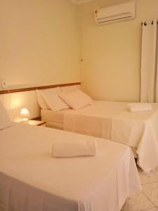 阿拉卡茹Pousada Aruamar的配有白色床单的客房内的两张床