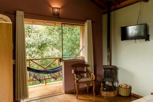 贡萨尔维斯Chalés Vale da Lua的客房设有窗户、椅子和电视。