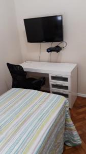 里约热内卢Quarto no Coração da Tijuca的一间卧室配有一张床和一张书桌及电视