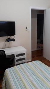 里约热内卢Quarto no Coração da Tijuca的一间卧室配有一张床和一张书桌及电视