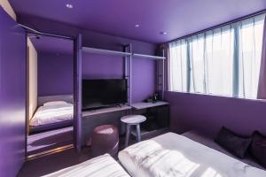 东京toggle hotel suidobashi TOKYO的紫色客房配有两张床和一台电视机