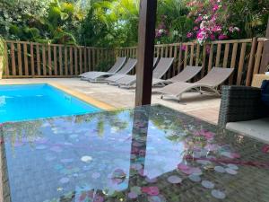 圣弗朗索瓦Titalee Lodge 3 Villas autour d'une piscine的玻璃桌、椅子和游泳池