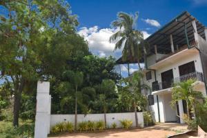 阿努拉德普勒Thinaya lake resort的白色的房子,有栅栏和树木
