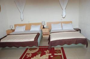 基加利步镇旅馆的一间带两张床的卧室和红色地毯