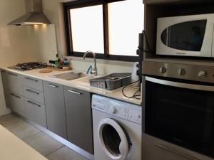 蓝海湾65/66 South Beach Apartment的厨房配有洗衣机和微波炉。