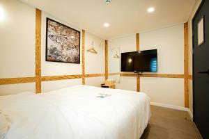 木浦市Geonmaek Stay的卧室配有白色的床和平面电视。