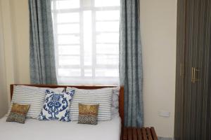 内罗毕Zanale Stays Furnished Apartment?的一张带蓝色和白色枕头的床和窗户