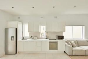 悉尼Oceanfront Tamarama Apartment: Best View in Sydney的白色的厨房配有冰箱和沙发