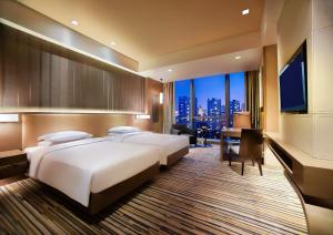 重庆重庆富力凯悦酒店的酒店客房设有两张床、一张桌子和一台电视。