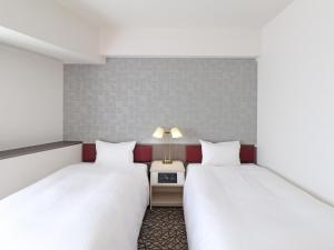 横滨横滨伊势佐木町岐山酒店(Chisun Hotel Yokohama Isezakicho) 的客房设有两张床和一张带台灯的桌子。