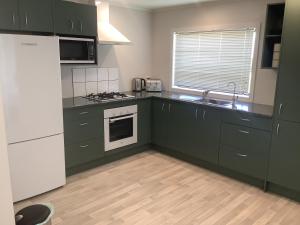 奥克兰Kaiaua Bayview Farm Apartment的厨房配有绿色橱柜和白色冰箱