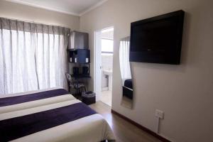 马塞卢Scenery Maqalika Guesthouse的配有一张床和一台平面电视的酒店客房