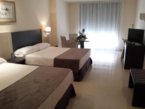 维拉Hotel Adaria Vera的酒店客房设有两张床和一张桌子。