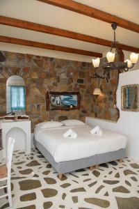 阿吉亚利拉其村公寓式酒店的一间卧室设有一张床和石墙