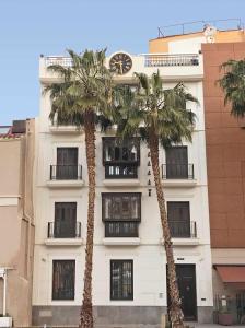 马拉加THE CLOCK HOUSE Luxury Urban Suites的两棵棕榈树,在一座带钟表的建筑前