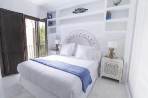 马拉加THE CLOCK HOUSE Luxury Urban Suites的白色的卧室设有白色的床和窗户。