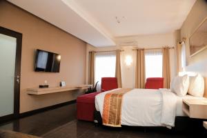 棉兰棉兰大酒店的酒店客房,配有一张床和两张红色椅子