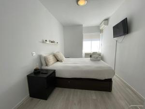 马德里Apartamento Cuzco的一间白色卧室,配有床和电视